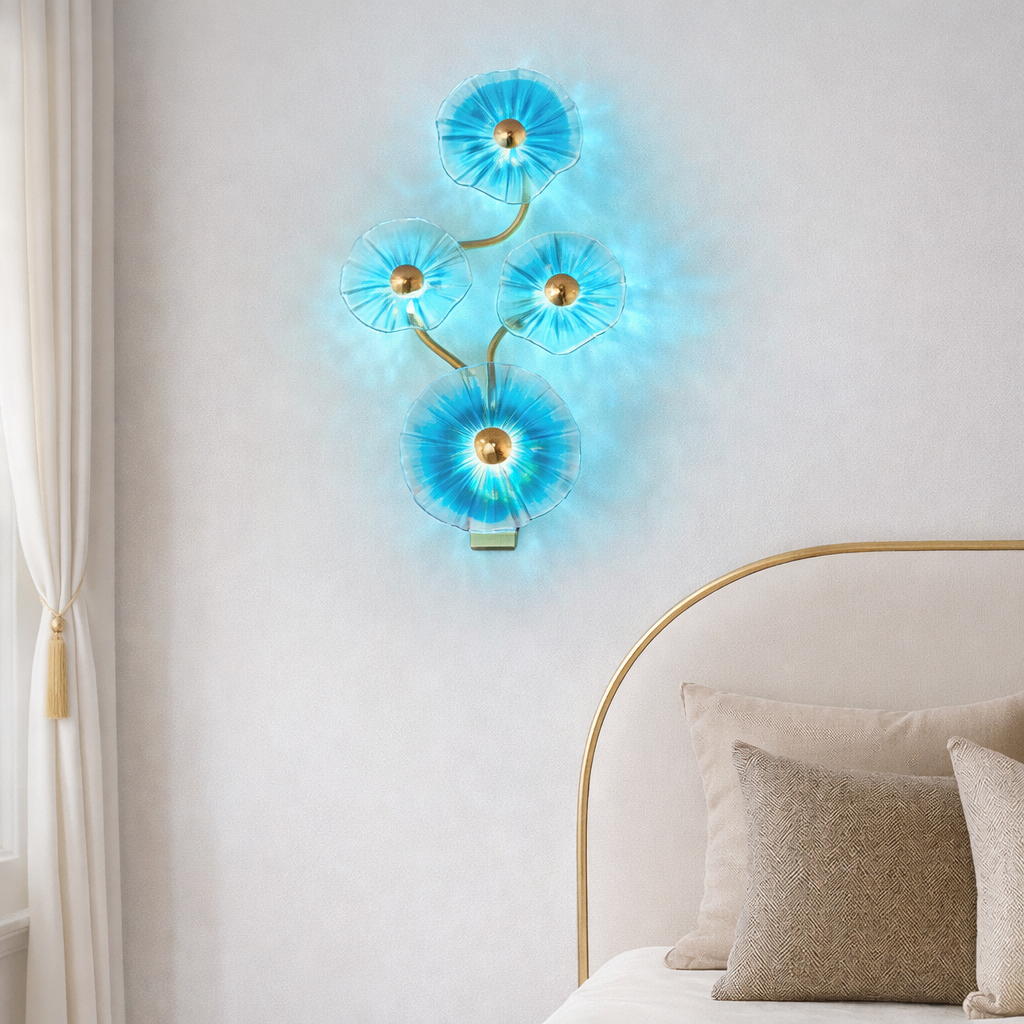 Azure Bloom designer crystal wall lighting with radiant blue floral glass and gold accents, mounted above a bed in a luxury bedroom setting.