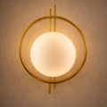 Celestial Halo Luxury Designer Wall Light with frosted globe and brass halo, mounted on textured wall. Ideal for modern home lighting décor.