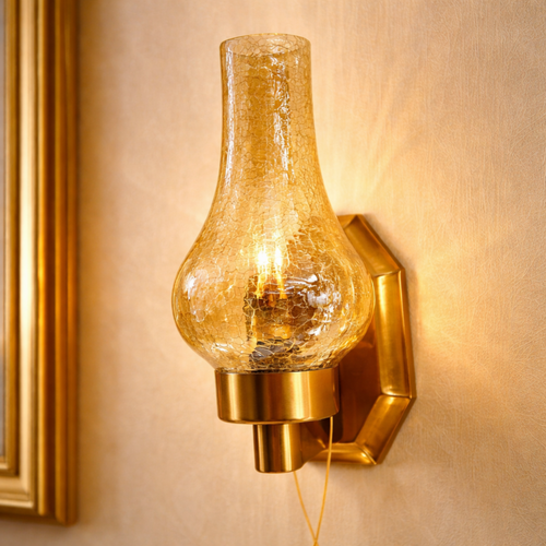AmberGlow Wall Sconce with luxury crackle glass and gold finish, mounted on a beige wall. Handcrafted lighting fixture for upscale interiors.