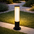 GlowColumn outdoor bollard light with LED illumination, installed along a modern garden pathway. Durable and elegant design for landscape lighting.