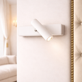 Contemporary adjustable modern LED wall light in matte white finish, mounted on a tufted wall panel, ideal for luxury bedroom lighting.