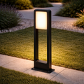 GlowFrame Modern LED Bollard Light illuminating a landscaped pathway at dusk. Sleek black frame adds elegance to outdoor garden lighting design.