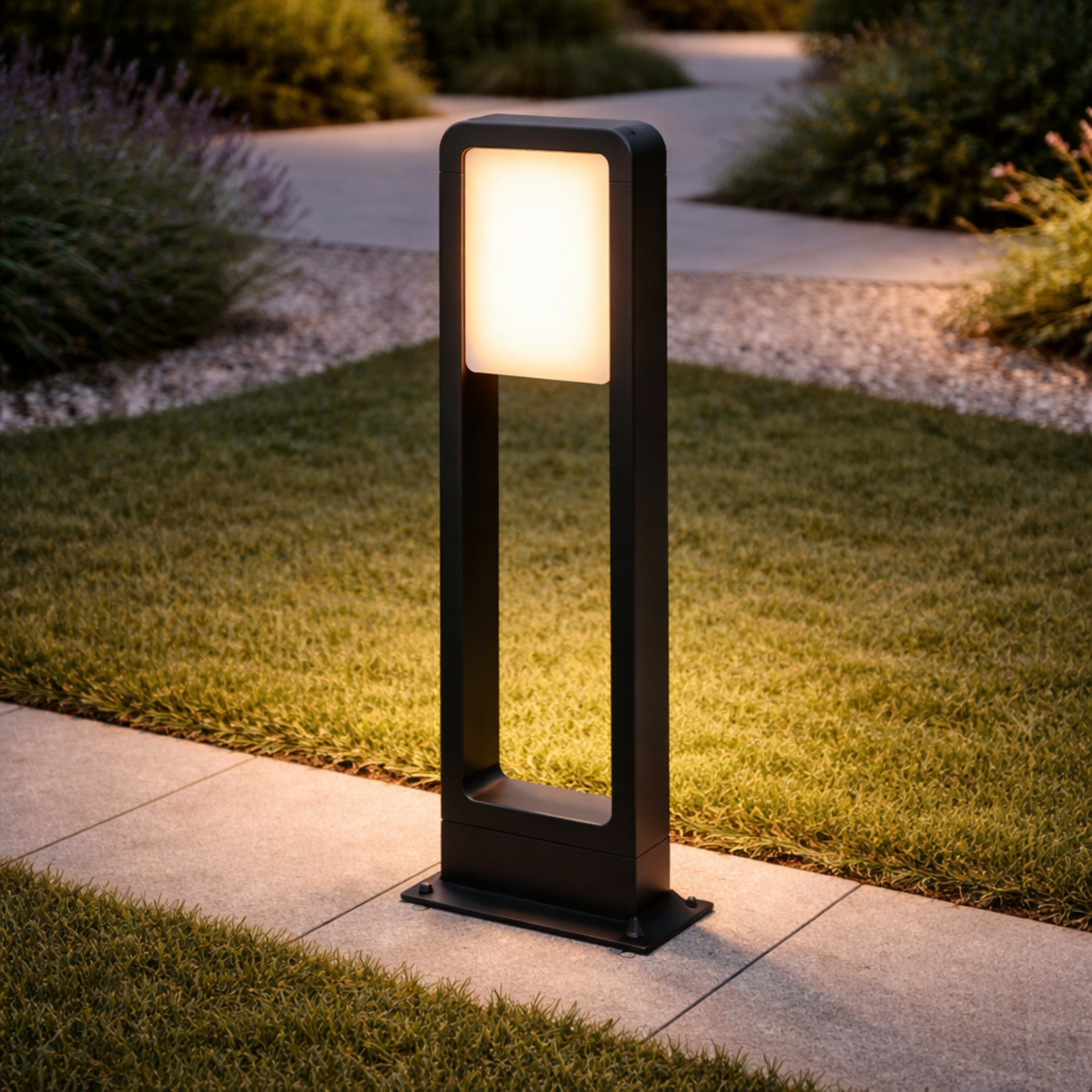 GlowFrame Modern LED Bollard Light illuminating a landscaped pathway at dusk. Sleek black frame adds elegance to outdoor garden lighting design.