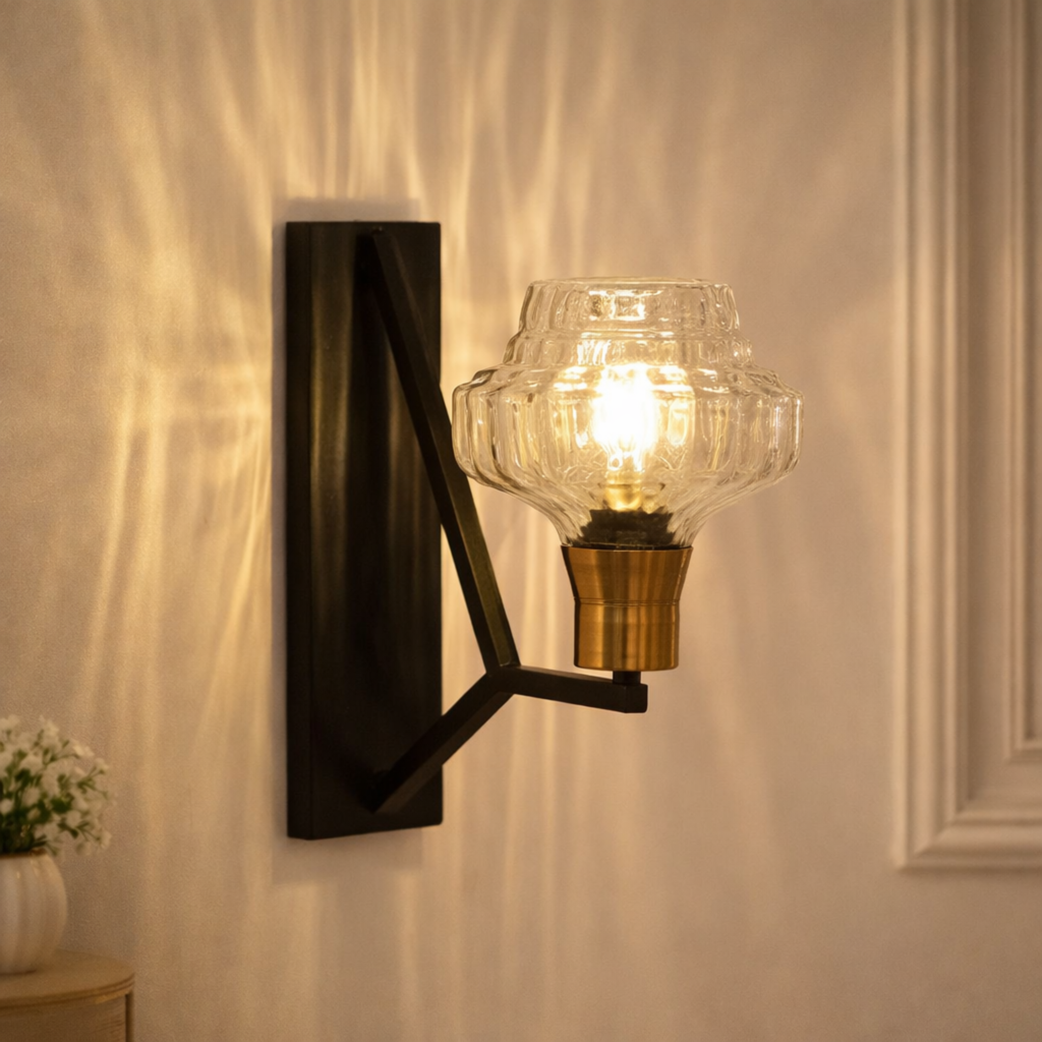 Aureon Prism Luxury Designer Wall Light with ribbed glass shade and brass base, mounted on a black frame, casting ambient light on a modern wall.