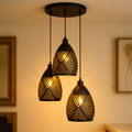 Luxury Black Cutwork Pendant Light - Nocturne Trio features three geometric-patterned shades with warm ambient lighting, ideal for modern interiors.