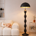 Imperial Noir Curve Luxury Floor Lamp India with sculptural black base and dome shade, placed in a modern living room with warm LED lighting.